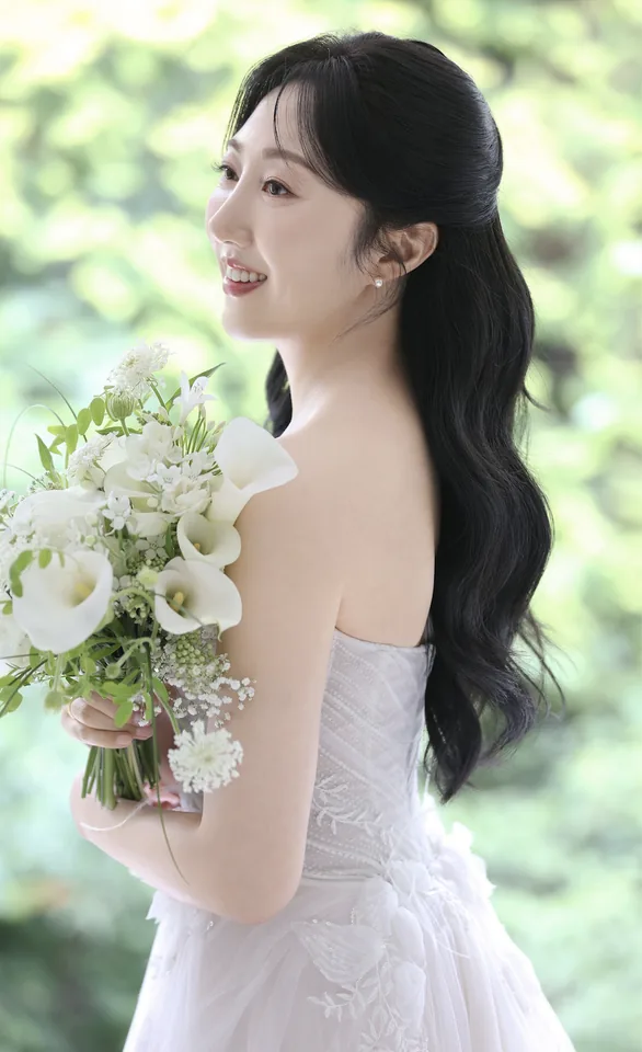 흰 꽃다발을 들고 옆을 바라보는 신부