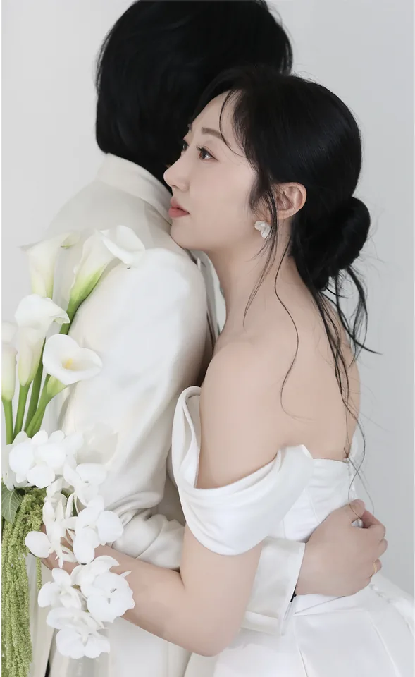 흰 배경 앞에서 포옹하는 신랑과 신부